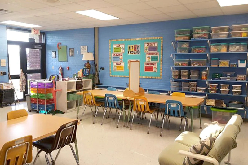 A classroom of kindergarten kids with colorful chairs, tables, toys, projectors and table lamp.