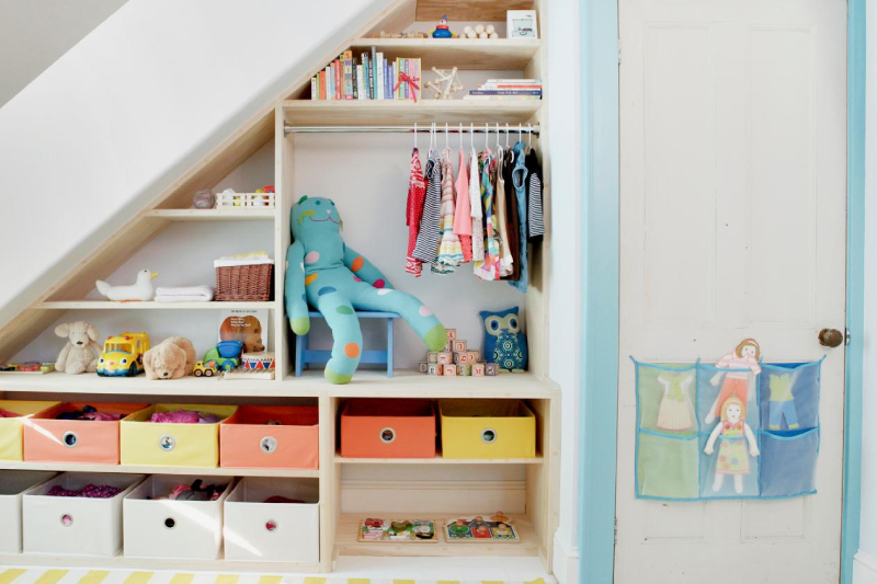 The space behind the staircase is transformed into shelves for storing clothes and toys and other box organizers.
